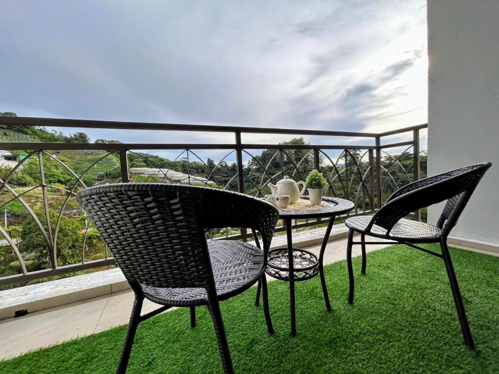 een terras met twee stoelen en een tafel op een balkon bij The Retreat Mountain & Sunrise view Hilltop Hotel Apartment in Cameron Highlands in Cameron Highlands