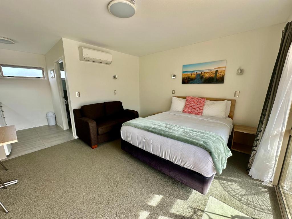 a bedroom with a bed and a chair in it at The Olive Motel in Coromandel Town