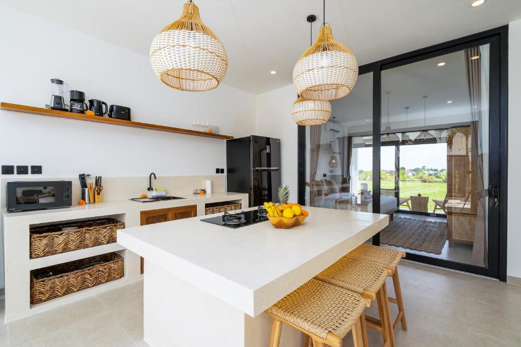 a kitchen with a white counter and some chairs at Villa Flambard in Canggu