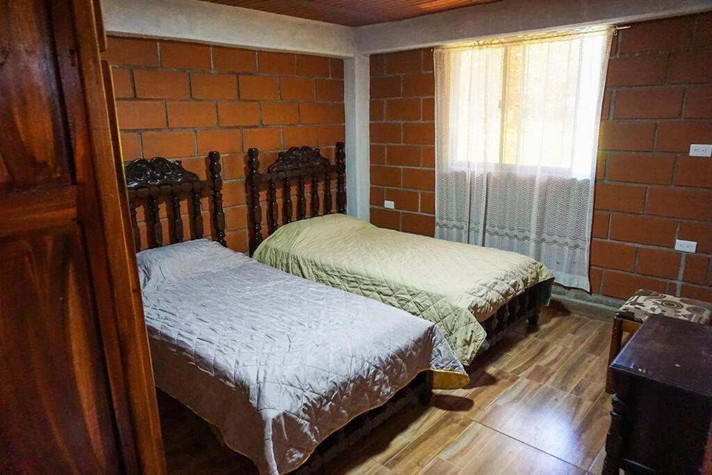 two beds in a room with a brick wall at Retro Finca Urrao - Peaceful Avocado Farm Retreat in Urrao