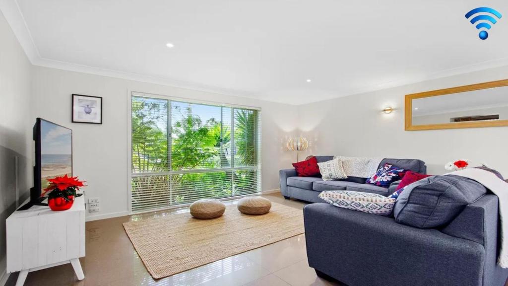 a living room with a blue couch and a tv at Amersham in Callala Bay