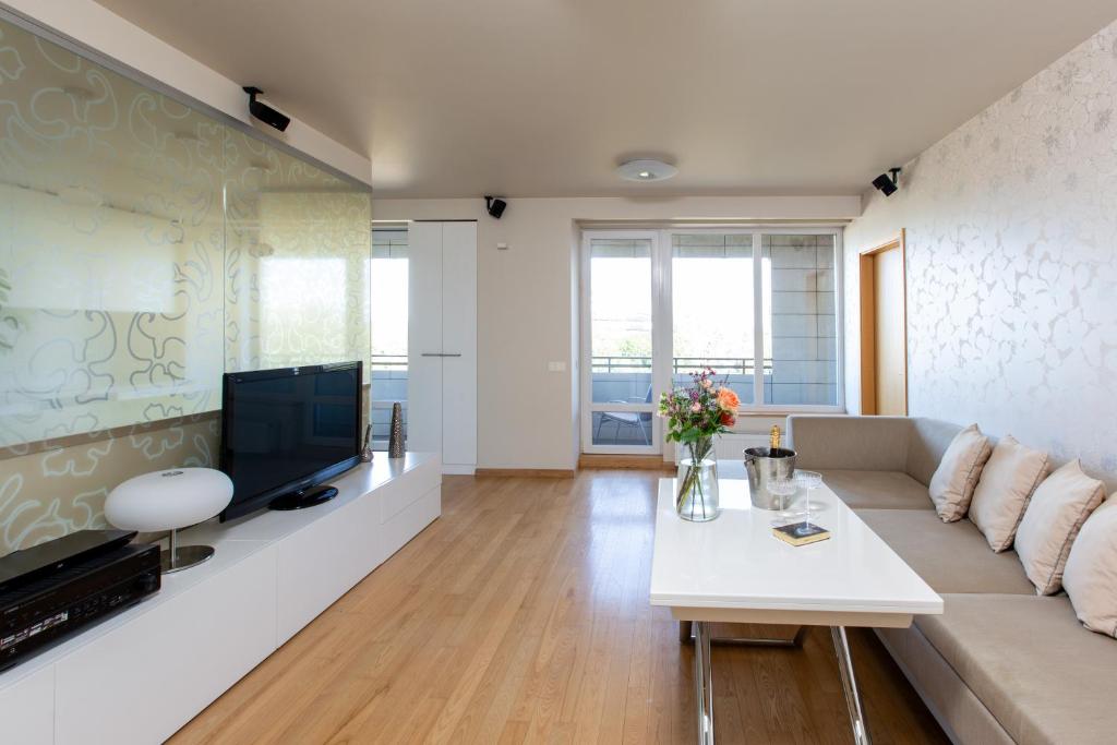 a living room with a couch and a tv at DRUSKININKŲ PANORAMA Apartamentai in Druskininkai