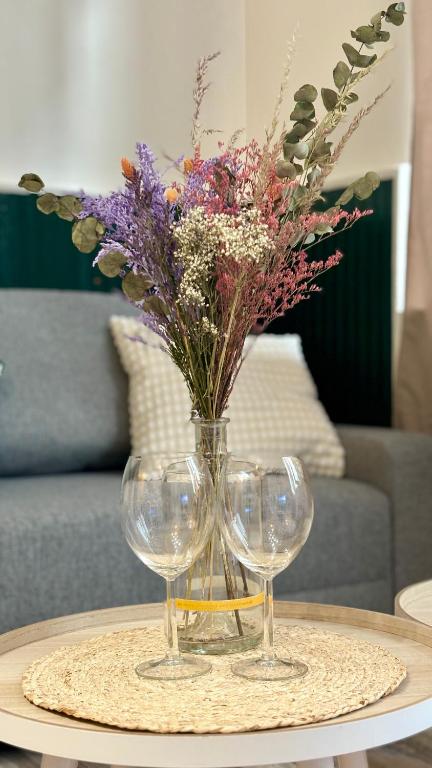 deux verres à vin et un vase de fleurs sur une table dans l'établissement Appartement calme et cosy - Proche centre, à Rouen