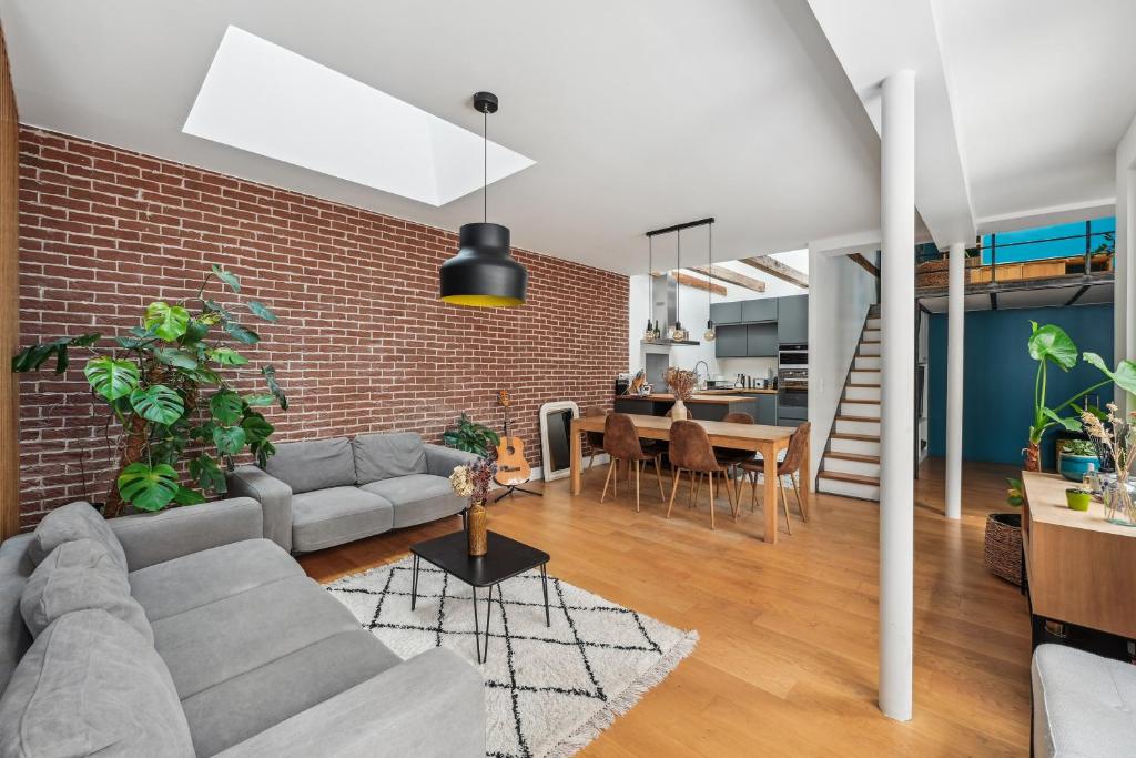 un salon avec un canapé et un mur de briques dans l'établissement Grandeur Cachée du 15e - avec parking, à Paris