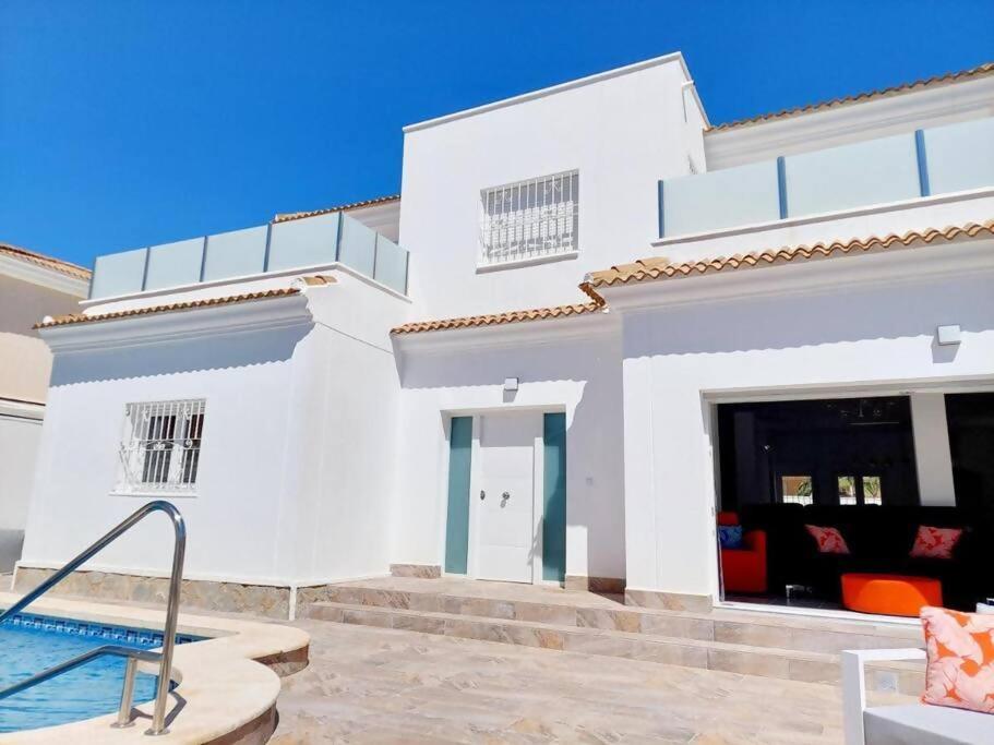a white house with a swimming pool in front of it at Casa Palma by Rental Hero in Los Alcázares