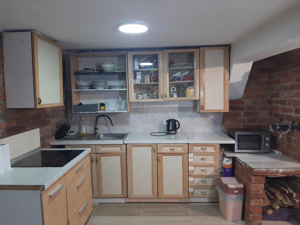a small kitchen with wooden cabinets and a sink at Nova Kuća na idiličnoj lokaciji sa mogućnosti korištenja pečenjare nije namijenjena malodobnoj djeci i osobama koje su osjetljive na miris dima in Šćapovec