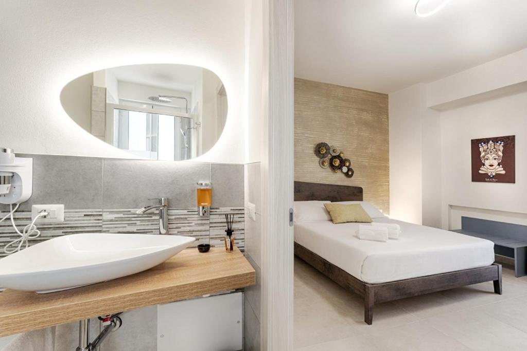 a bathroom with a sink and a bed and a mirror at Belvedere Barocco in Ragusa