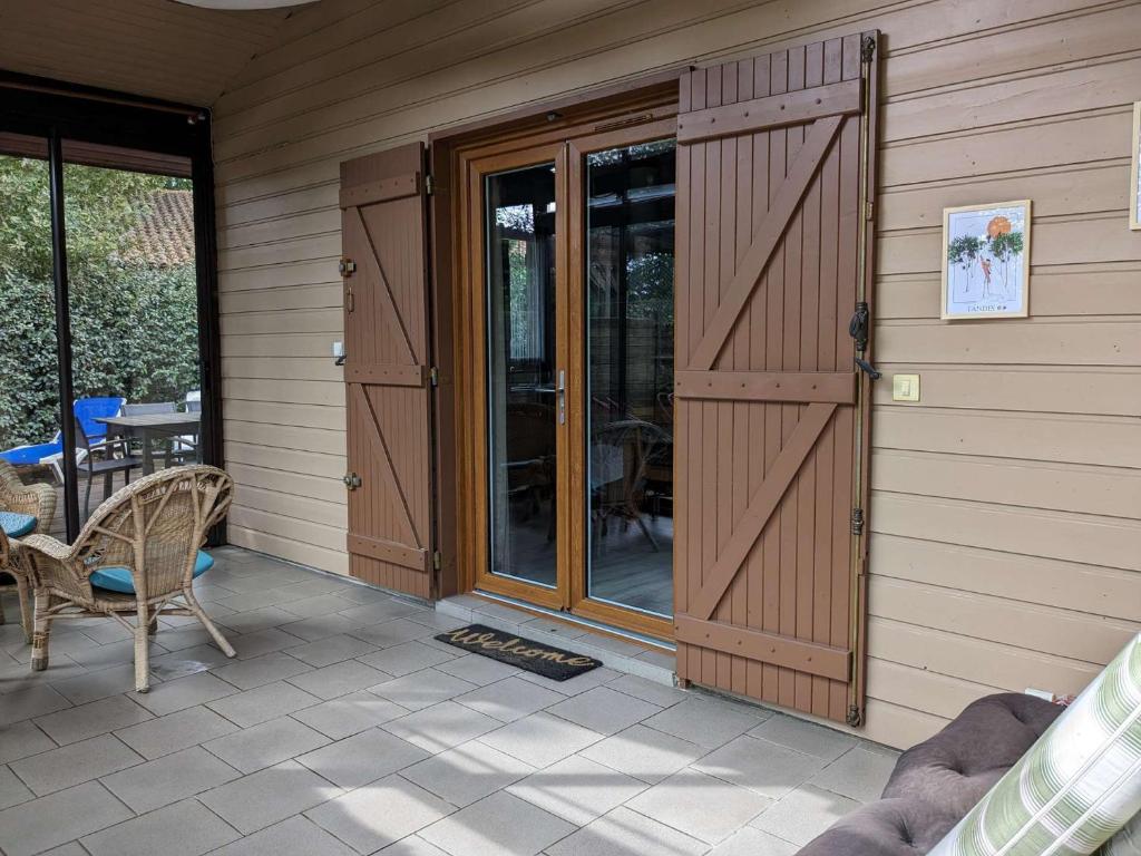 une maison avec une porte en bois et une terrasse dans l'établissement Biscarrosse Lac Charmante Maison en bois 9 couchages proche lac, à Biscarrosse