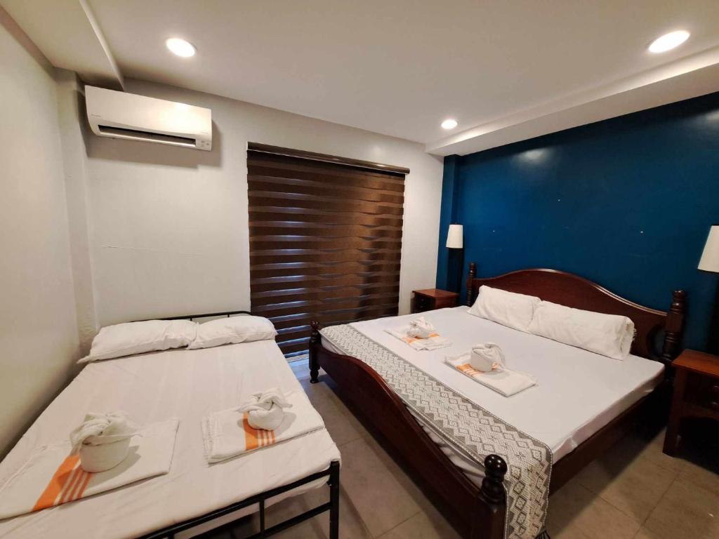 a hotel room with two beds and a blue wall at 2F Vivere Condo - Govantes Properties in Vigan