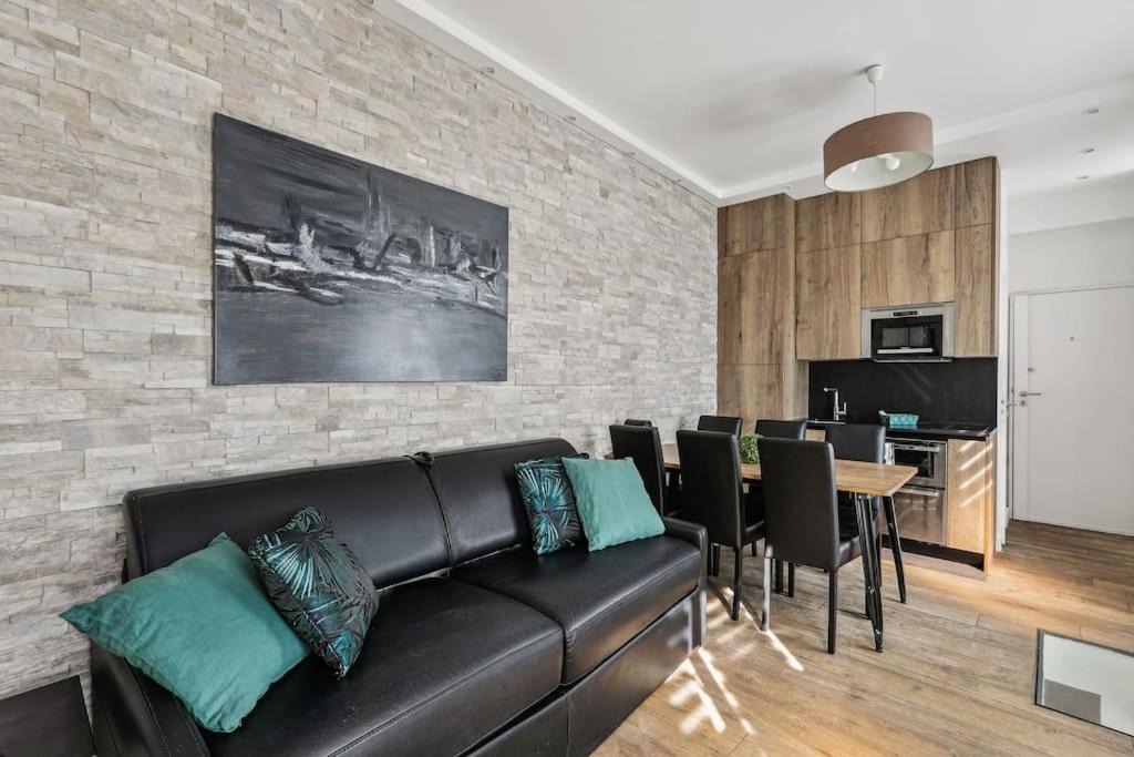 a living room with a black leather couch and a table at 03 Tour Eiffel Appartement pour 7 personnes in Paris