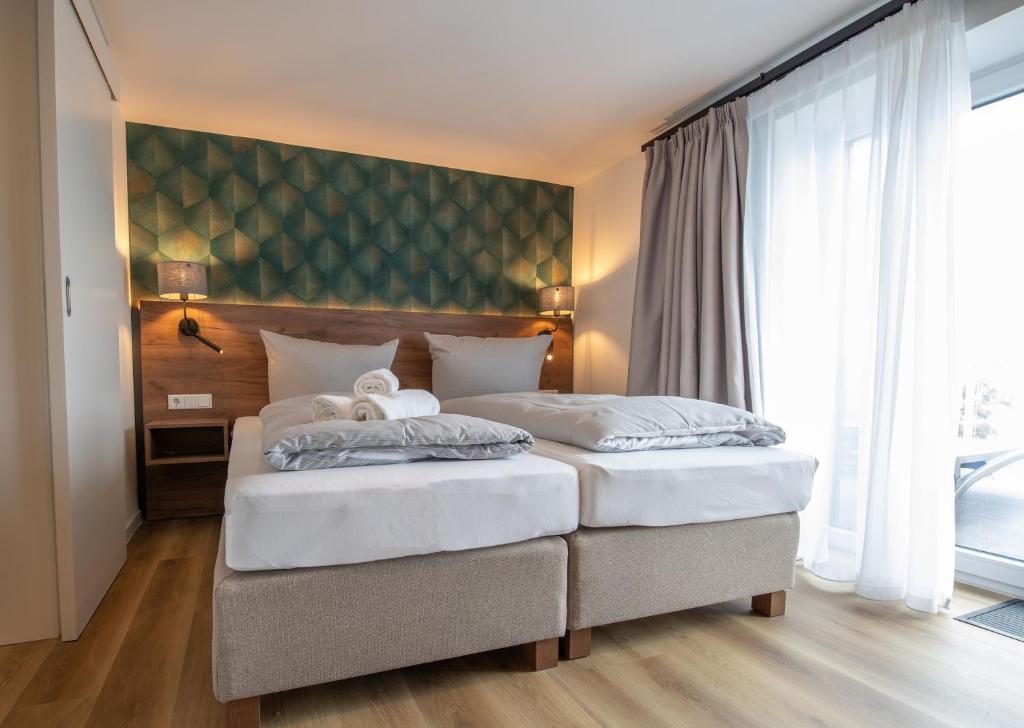 two beds in a bedroom with a green wall at Küstenblick in Carolinensiel