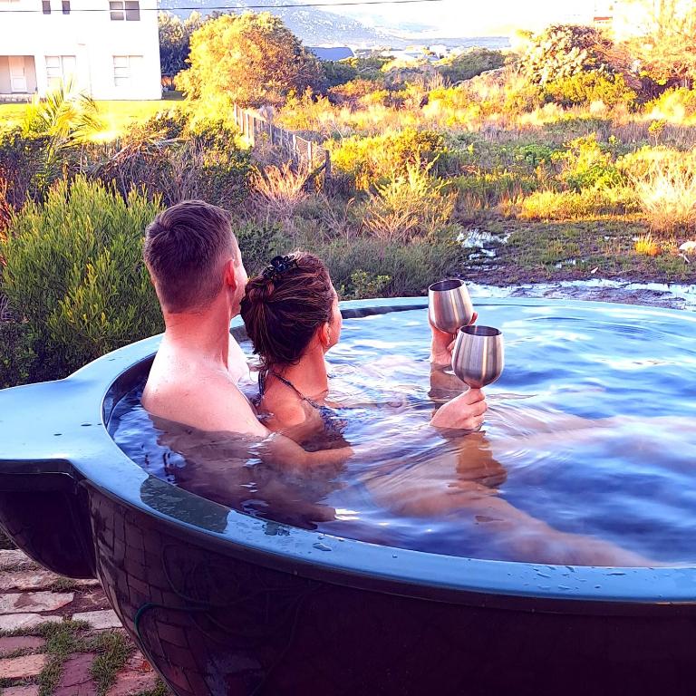 a man and woman in a hot tub with wine glasses at Edible Shores in Pringle Bay