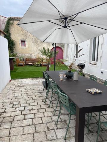 - une table noire avec un parasol blanc sur la terrasse dans l'établissement Propriété IØ8 - Oléron, à Saint-Pierre-dʼOléron