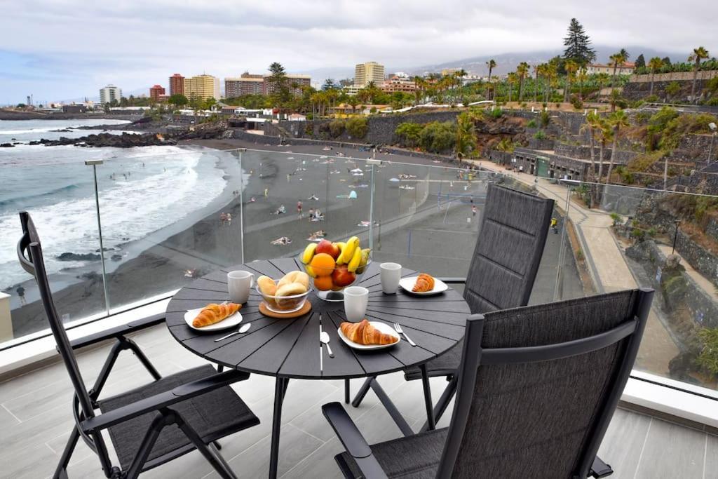 a table with food on a balcony with a view of the beach at La Sirena Playa C in Puerto de la Cruz