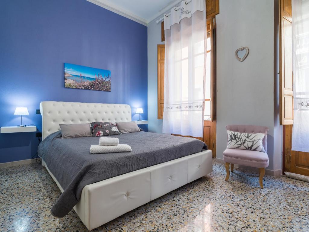 a blue bedroom with a large bed and a chair at Homeboutique in Cagliari