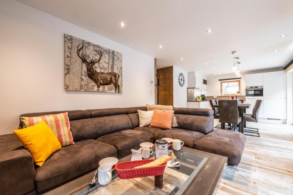 un salon avec un canapé marron et une table dans l'établissement OURSON - Appartement 3 chambres / 3 salles de bains, à Morzine
