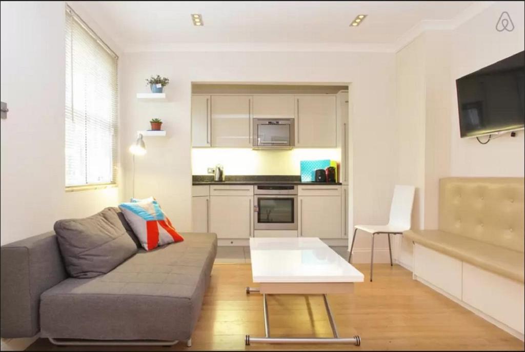 ein Wohnzimmer mit einem Sofa und einem Tisch in der Unterkunft Notting Hill Gardens Apartments in London