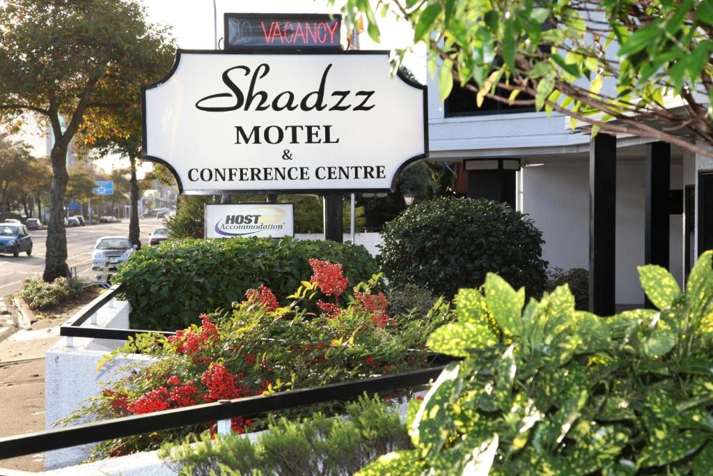 a sign for a hotel with some plants in front of it at Shadzz Motel in Palmerston North