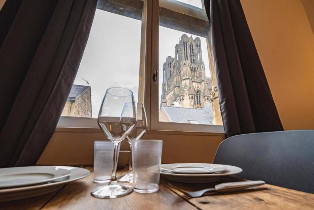 - une table avec deux verres à vin et une fenêtre dans l'établissement Bulle, vue Cathédrale incroyable, à Reims