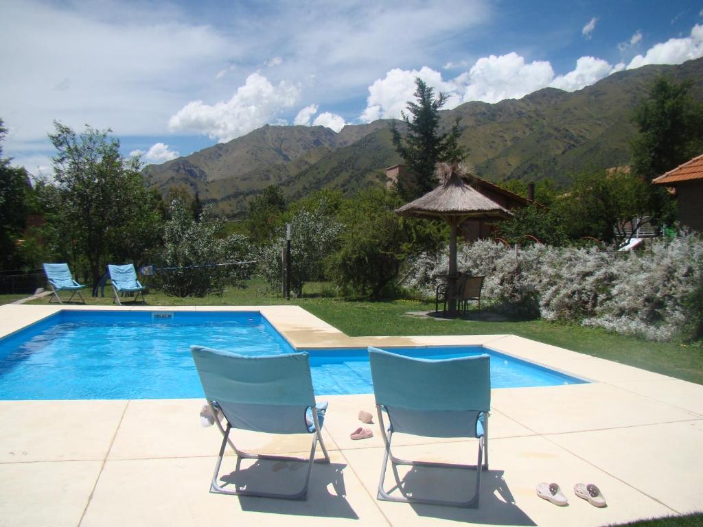 two chairs and a swimming pool with mountains in the background at Rumbo 020 Apart in Merlo