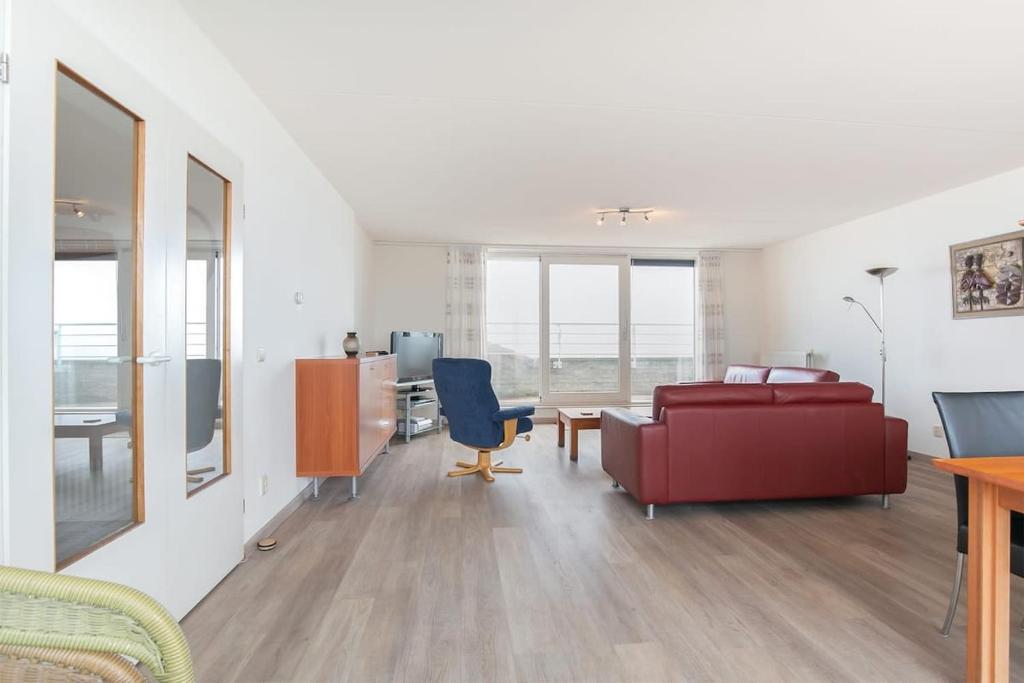 a living room with a red couch and a desk at Hello Zeeland - Appartement Port Scaldis 11-112 in Breskens