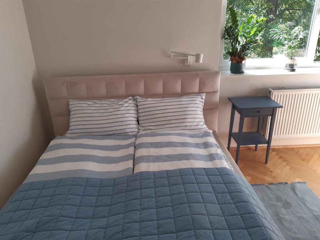 a bedroom with a bed with a blue comforter and a window at Karmel Apartment in Warsaw
