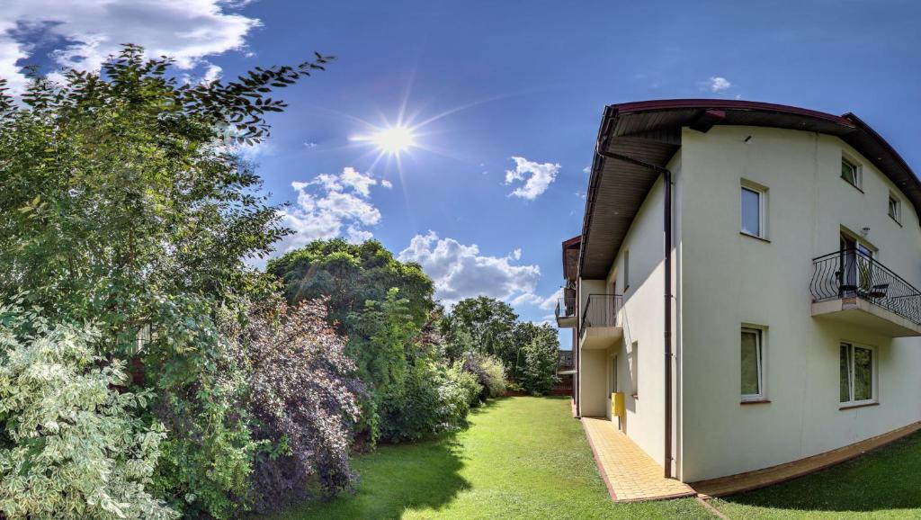 an exterior view of a white building with trees at Casablanca Pokoje i Apartamenty in Kazimierz Dolny