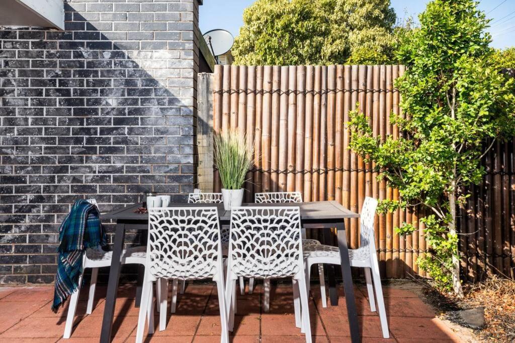 a table and chairs on a patio with a fence at Belmont 3BR Townhome by Short and Long Stays in Belmont