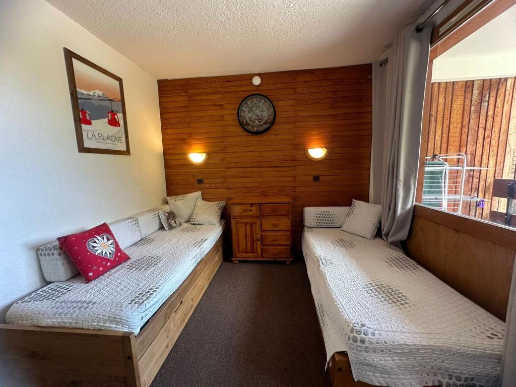 Cette chambre comprend deux lits et une horloge murale. dans l'établissement Studio divisible fonctionnel · Ski aux pieds - FR-1-181-2688, à La Plagne Tarentaise