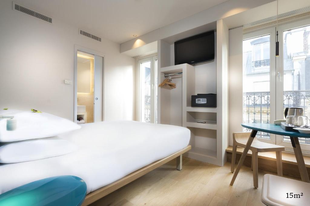 a white bedroom with a bed and a table at Hotel Andréa in Paris