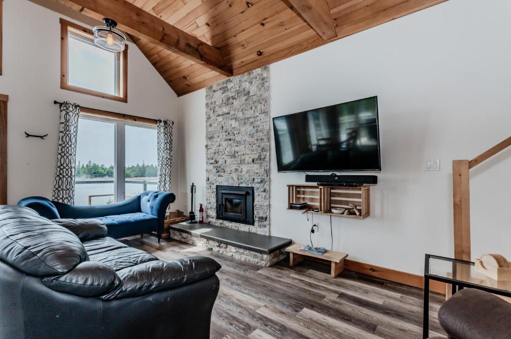 een woonkamer met een bank en een open haard bij Elysium - Perfect Waterfront for the Holidays in Red Bay