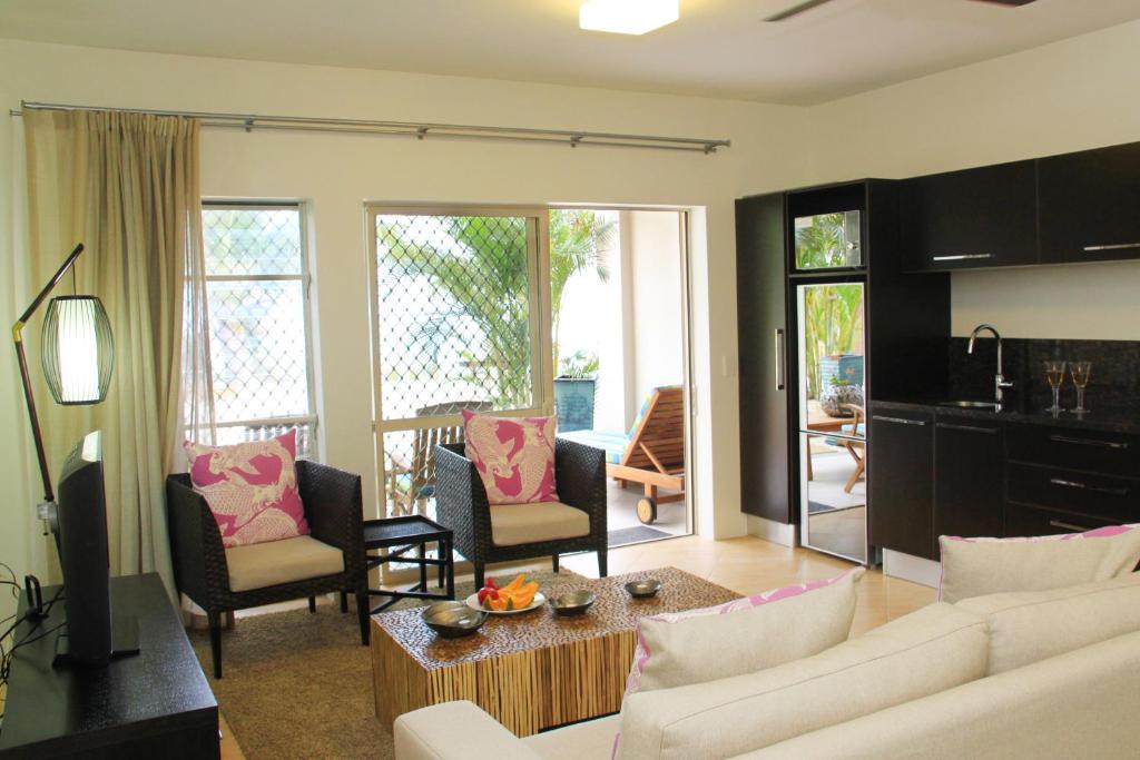 a living room with a white couch and chairs at Moana Sands Beachfront Villas in Rarotonga