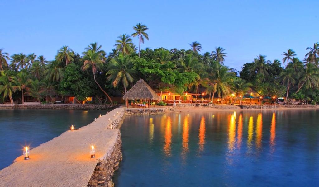 Toberua Island Resort في Toberua: شاطئ فيه منتجع والنخيل بالليل
