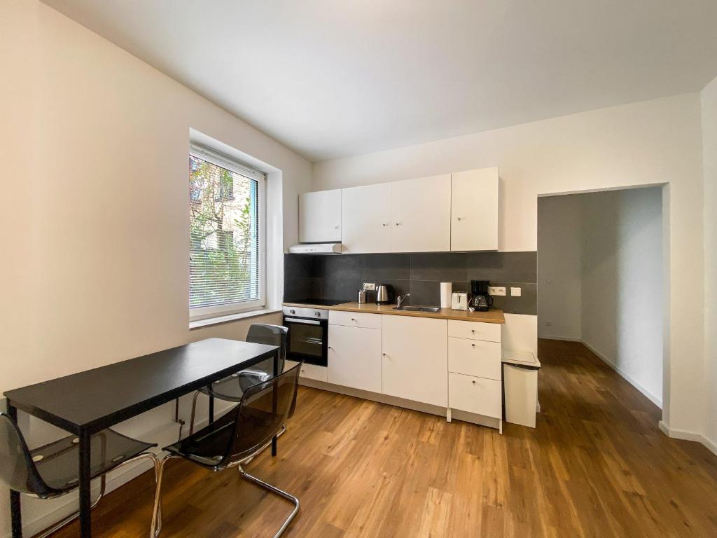 a kitchen with white cabinets and a black table at G&G Apartments in Krefeld