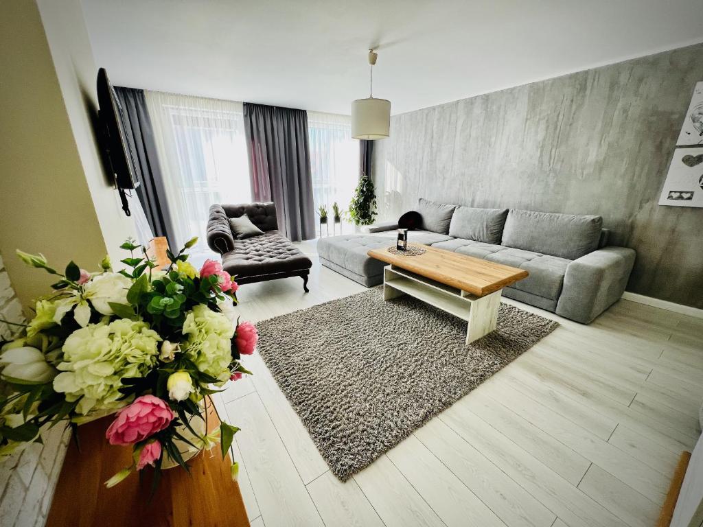sala de estar con sofá, mesa y flores en Kwartał Dominikański, en Kamień Pomorski