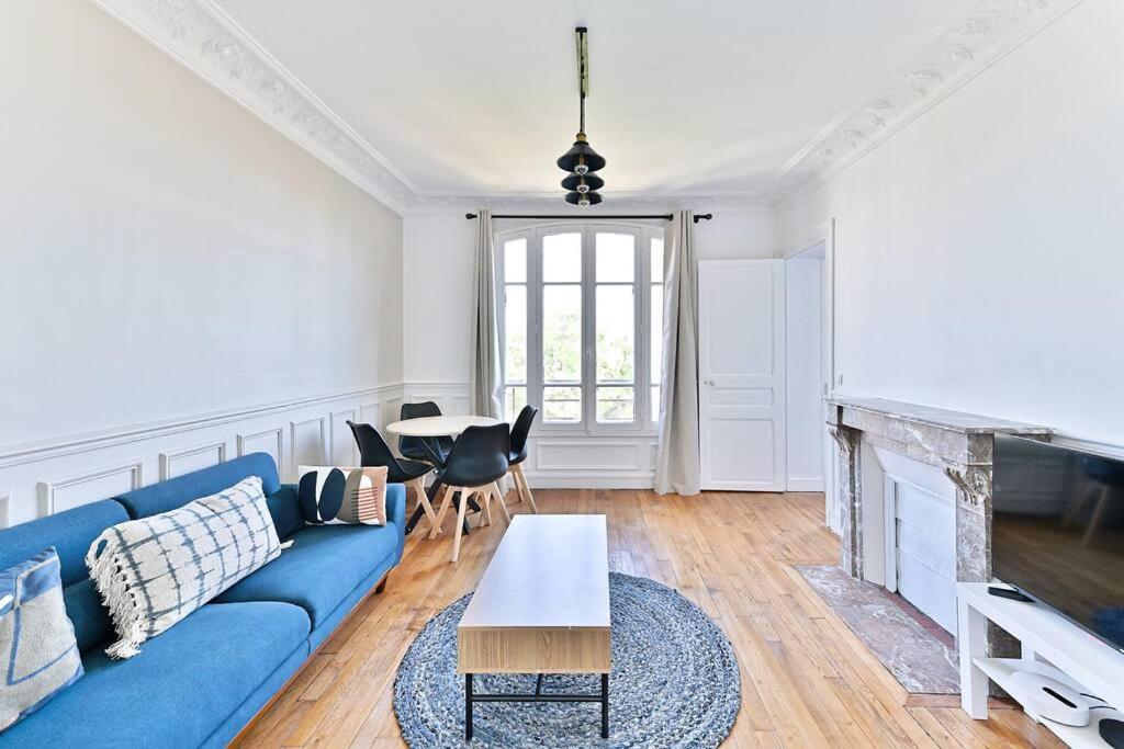 un salon avec un canapé bleu et une table dans l'établissement Appartement lumineux Banlieue Parisienne - III, à Puteaux