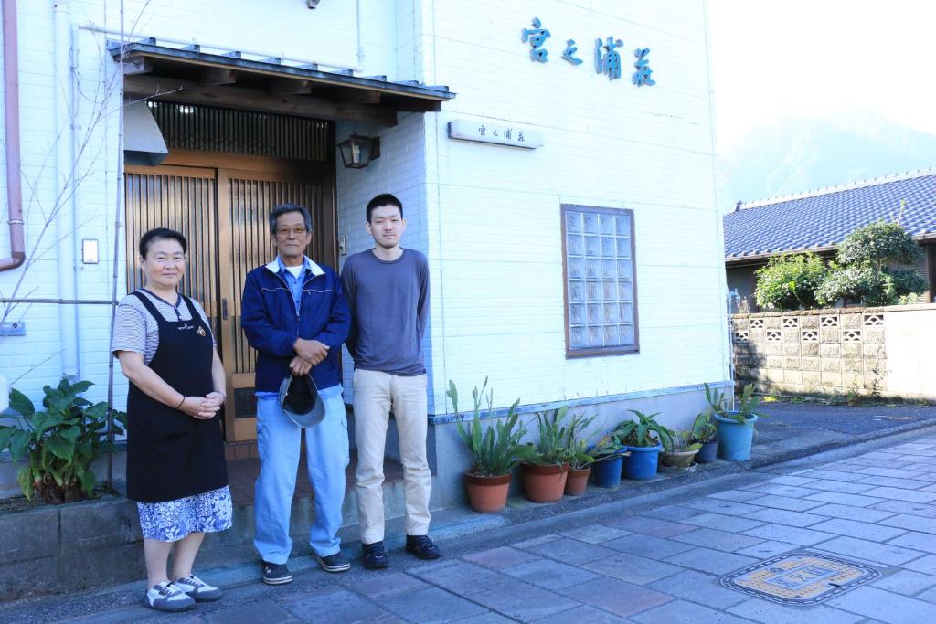 three men standing in front of a house at Miyanouraso in Yakushima