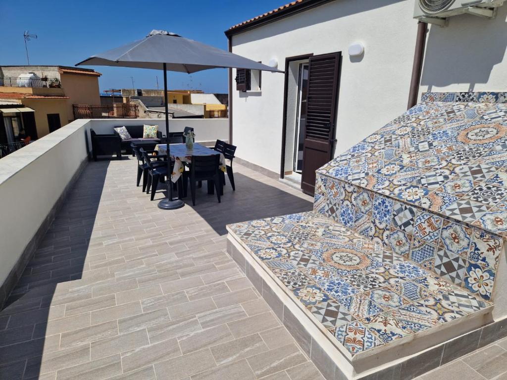 a balcony with a table and chairs and an umbrella at Il Cavaliere Apartment in Capaci