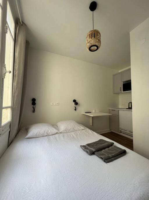 - une chambre avec un lit blanc et une serviette dans l'établissement Small, Studio Cosy, à Reims
