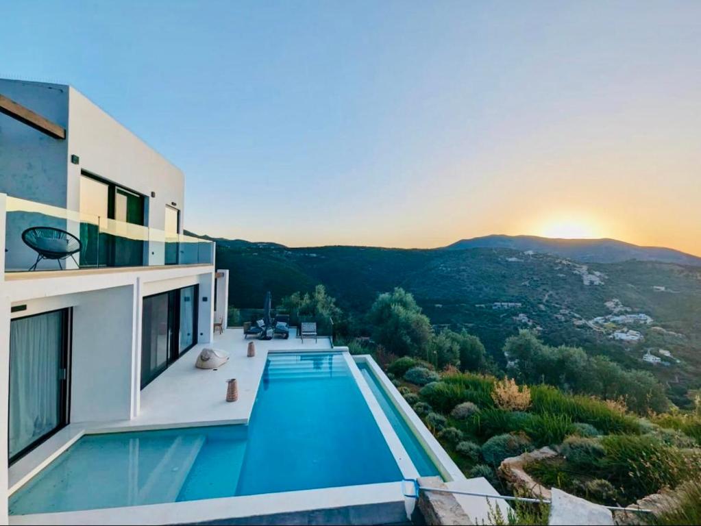 a villa with a swimming pool and a sunset at The Cove Sivota Bay in Sivota