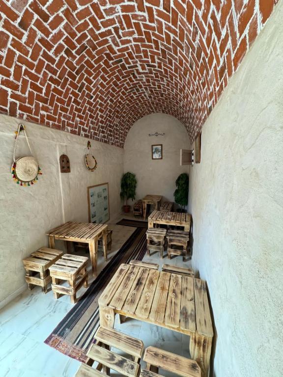 a room with wooden tables and a brick wall at Dar alibaba in Douz