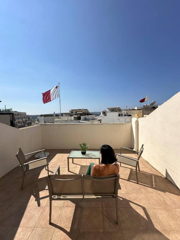 a woman sitting in a chair on a roof at Radiant 2BED penthouse Mellieha!! by Homely in Ix-Xagħra taʼ Barra
