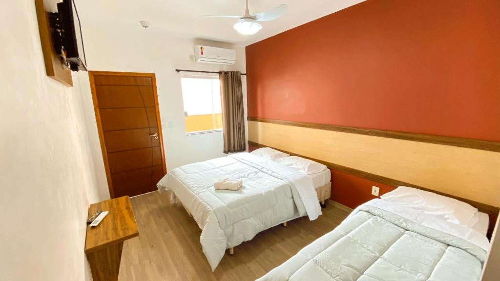 Un dormitorio con dos camas y una pared roja. en Hotel Capital da Fe, en Aparecida