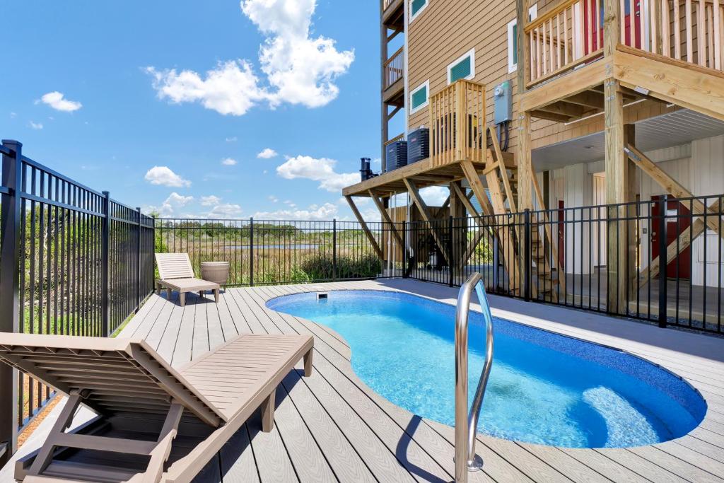 een dek met een zwembad, een bank en een gebouw bij Oceanside Oasis by Sea Scape Properties in North Topsail Beach