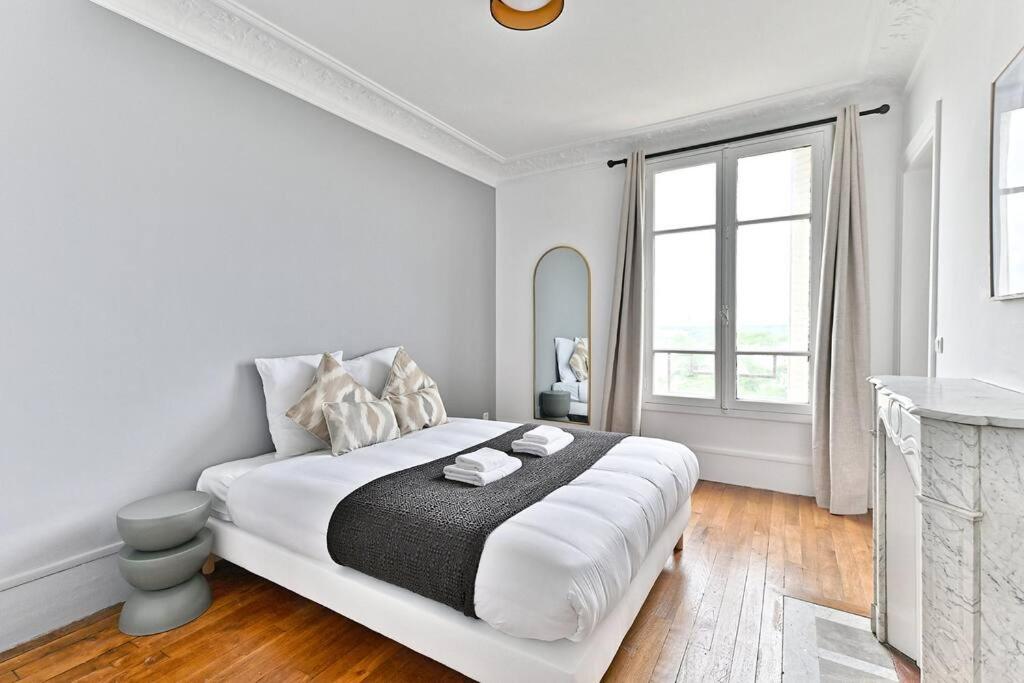 une chambre blanche avec un grand lit et une fenêtre dans l'établissement Appartement Vue panoramique sur la capitale - II, à Puteaux