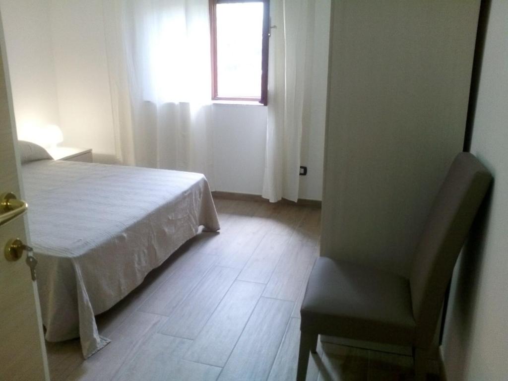 a bedroom with a bed and a chair and a window at B & B La Magnolia in Specchiolla