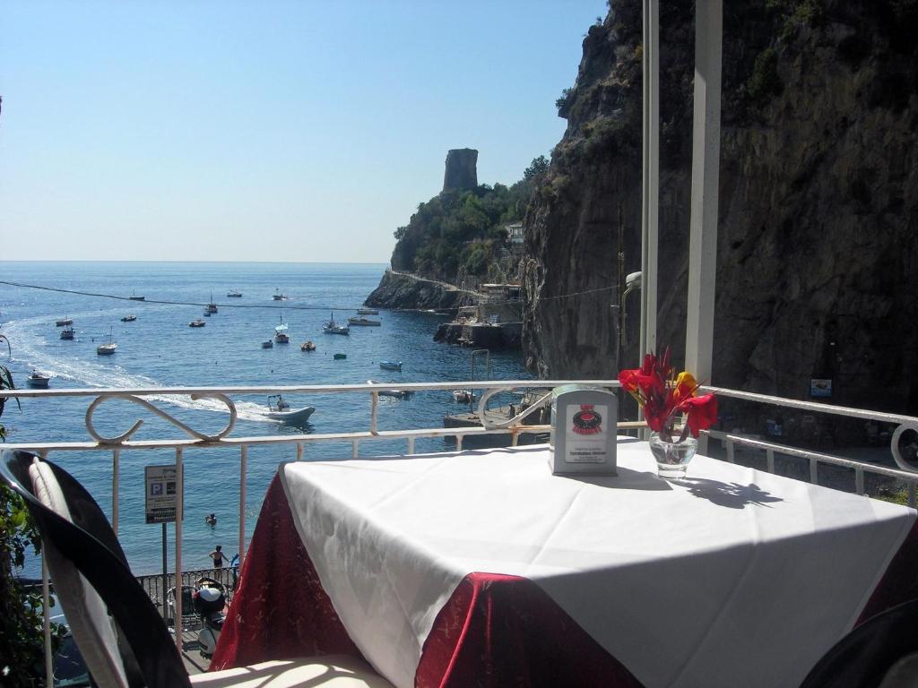 a table on a balcony with a view of the ocean at Hotel La Conchiglia in Praiano