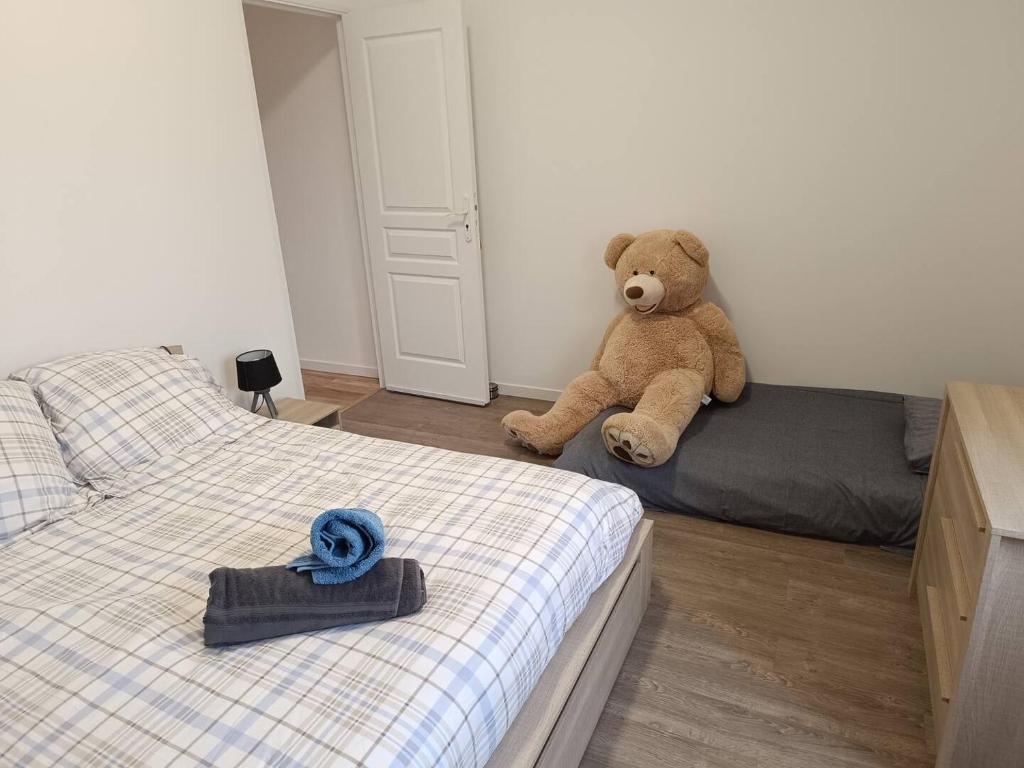 - un ours en peluche assis sur un lit dans une chambre dans l'établissement Appart sci phlb, à Saint-Rémy-lès-Chevreuse