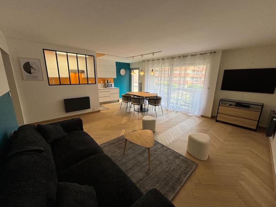 un salon avec un canapé noir et une table dans l'établissement Carré D'OR Dahlia 7 Pers avec Parking, à Le Touquet-Paris-Plage