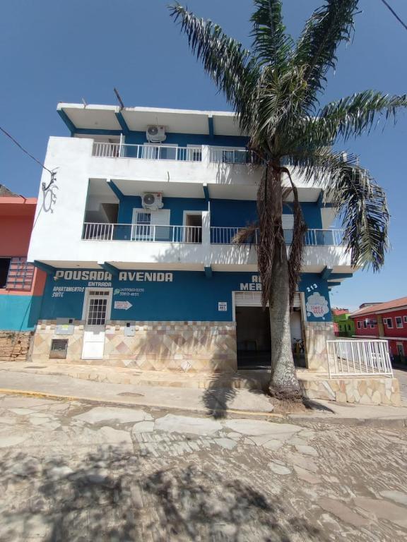 a building with a palm tree in front of it at Apartamento avenida 04 com ar condicionado in São Thomé das Letras